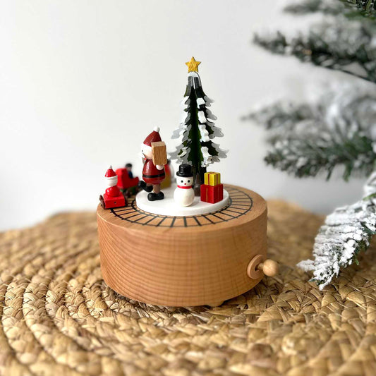 Wooden Christmas music box with Santa Claus and tree on a woven surface