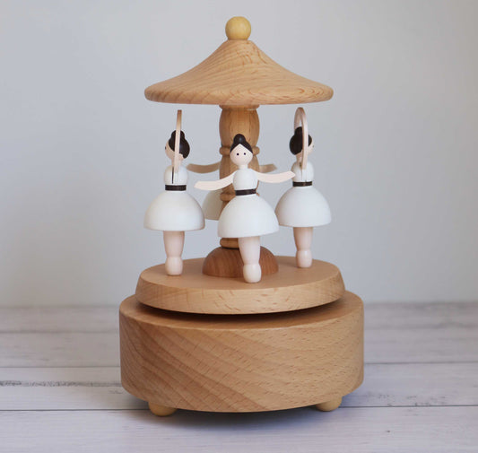 Wooden music box with ballerina figurines on a plain background