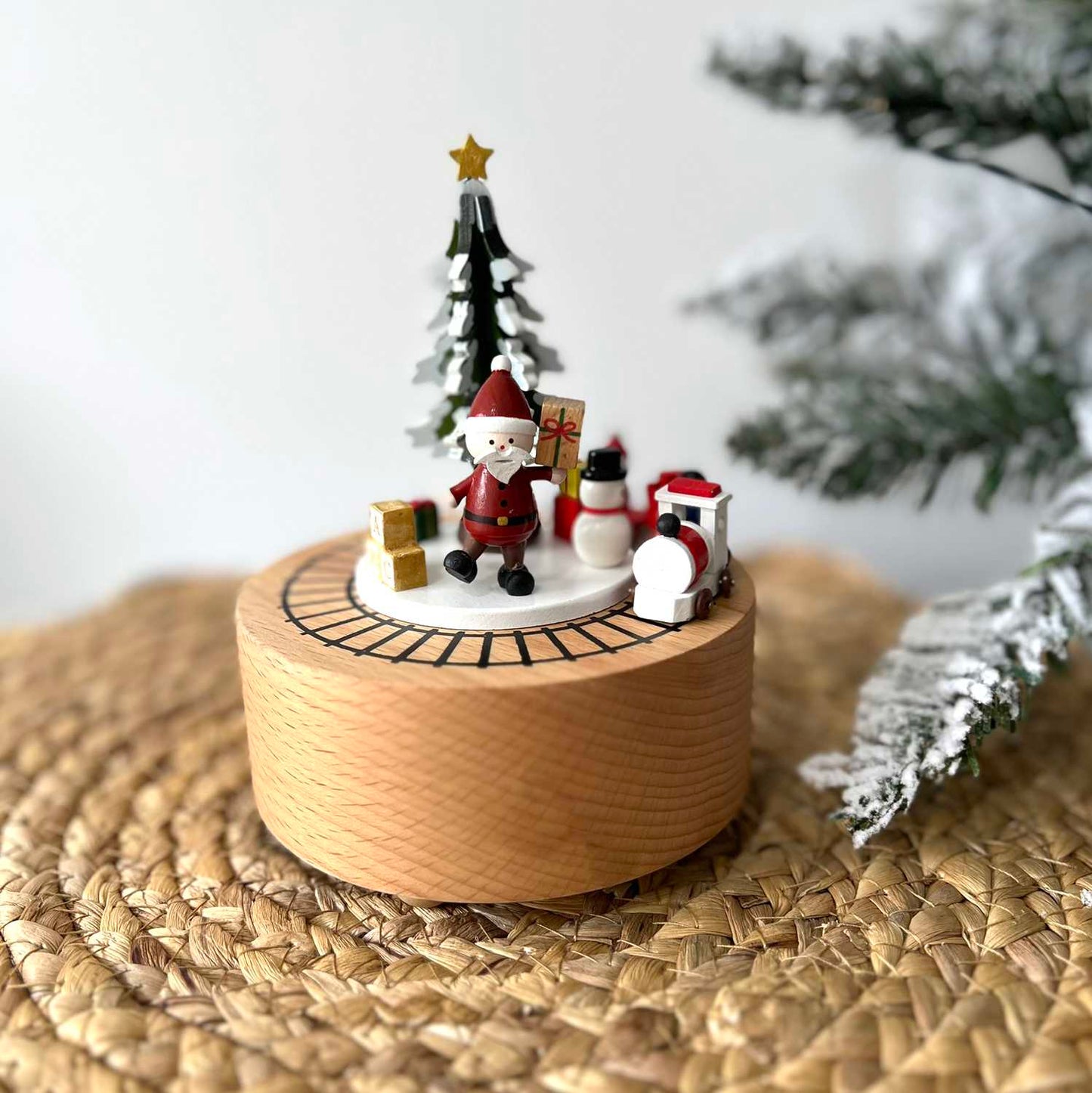 Wooden Christmas decoration with Santa Claus, snowman, and tree on a woven surface.