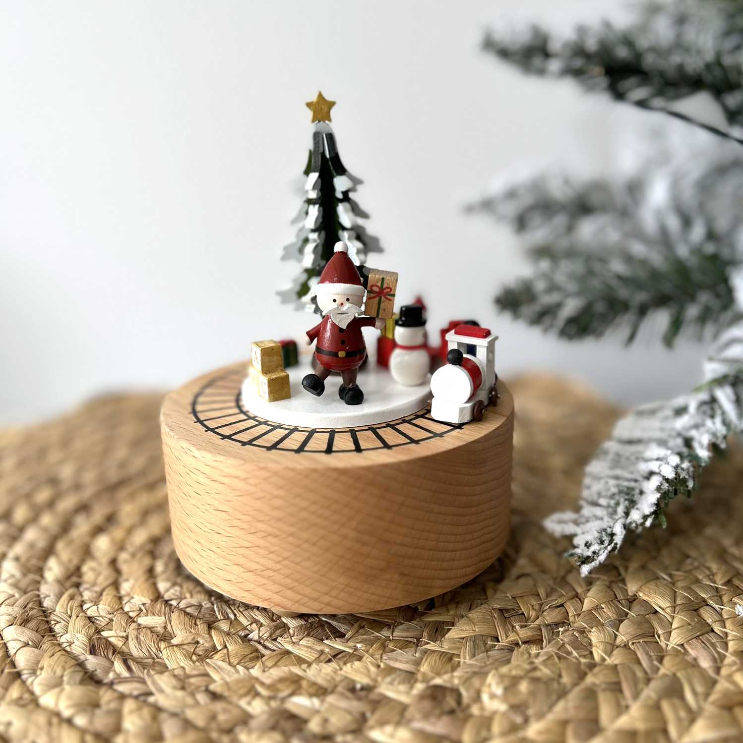Wooden Christmas decoration with Santa Claus, snowman, and tree on a woven surface.