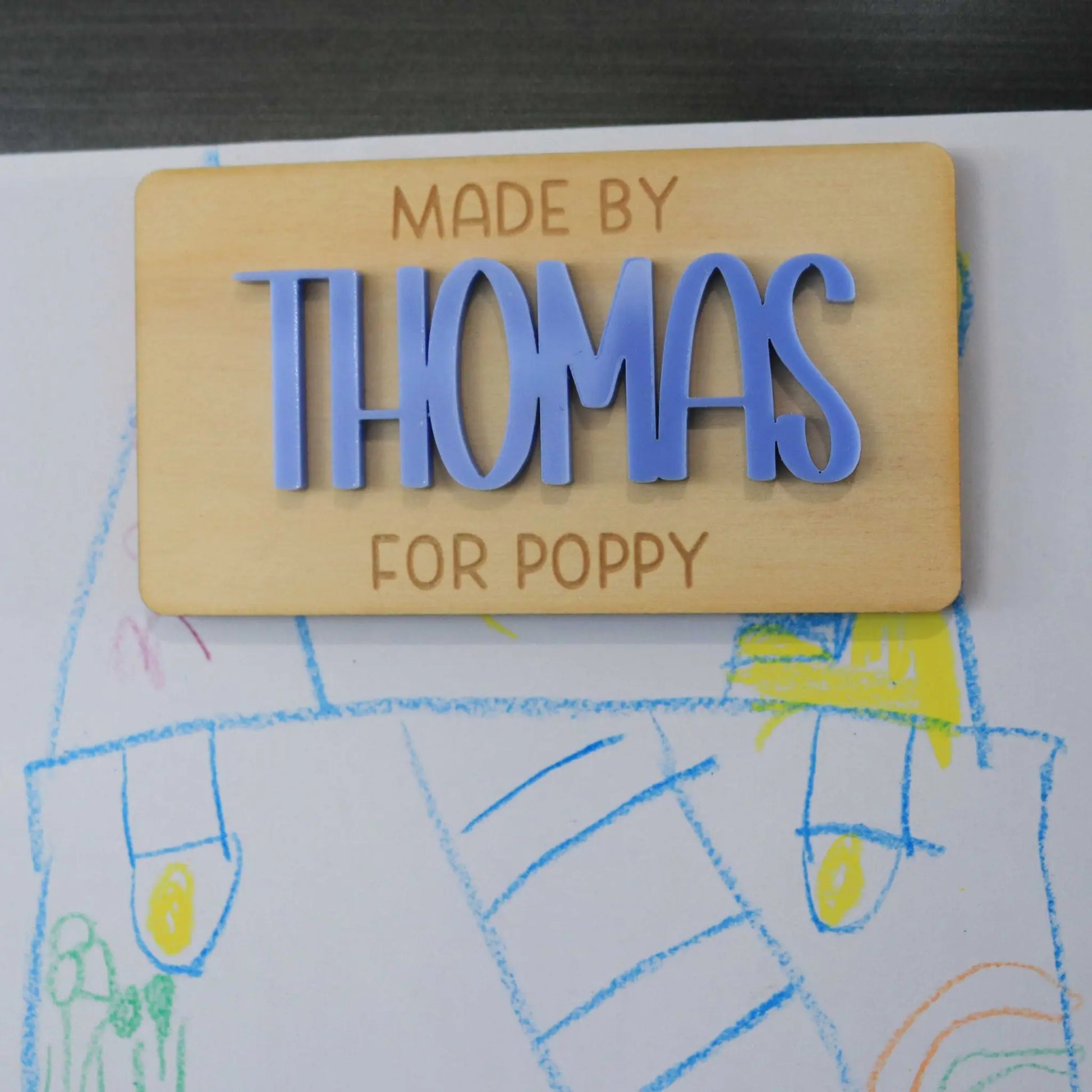 Custom acrylic and wood fridge magnet holding artwork 