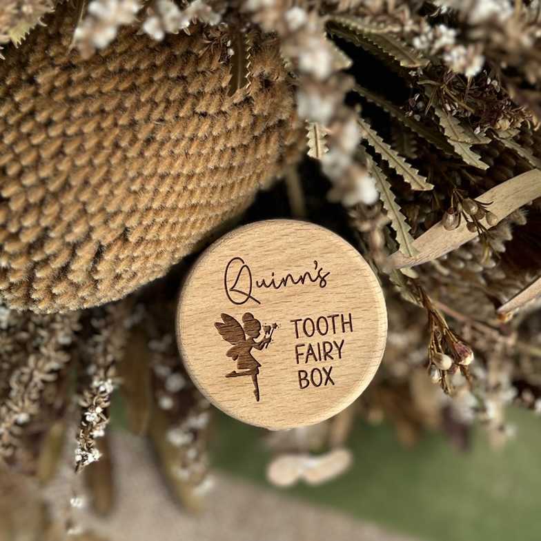 Wooden tooth fairy box with 'Quinn's Tooth Fairy Box' engraving on a textured surface.
