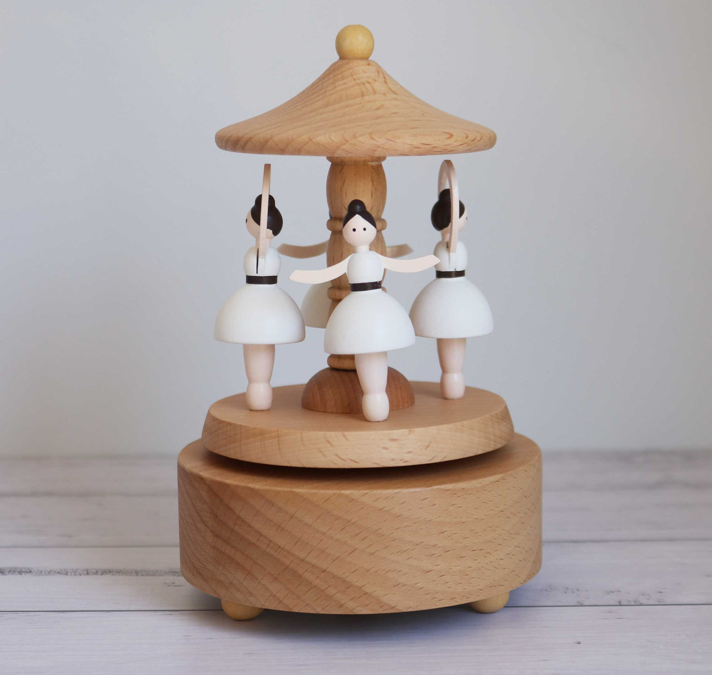 Wooden music box with ballerina figures on a plain background