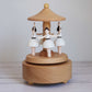 Wooden music box with ballerina figurines on a plain background